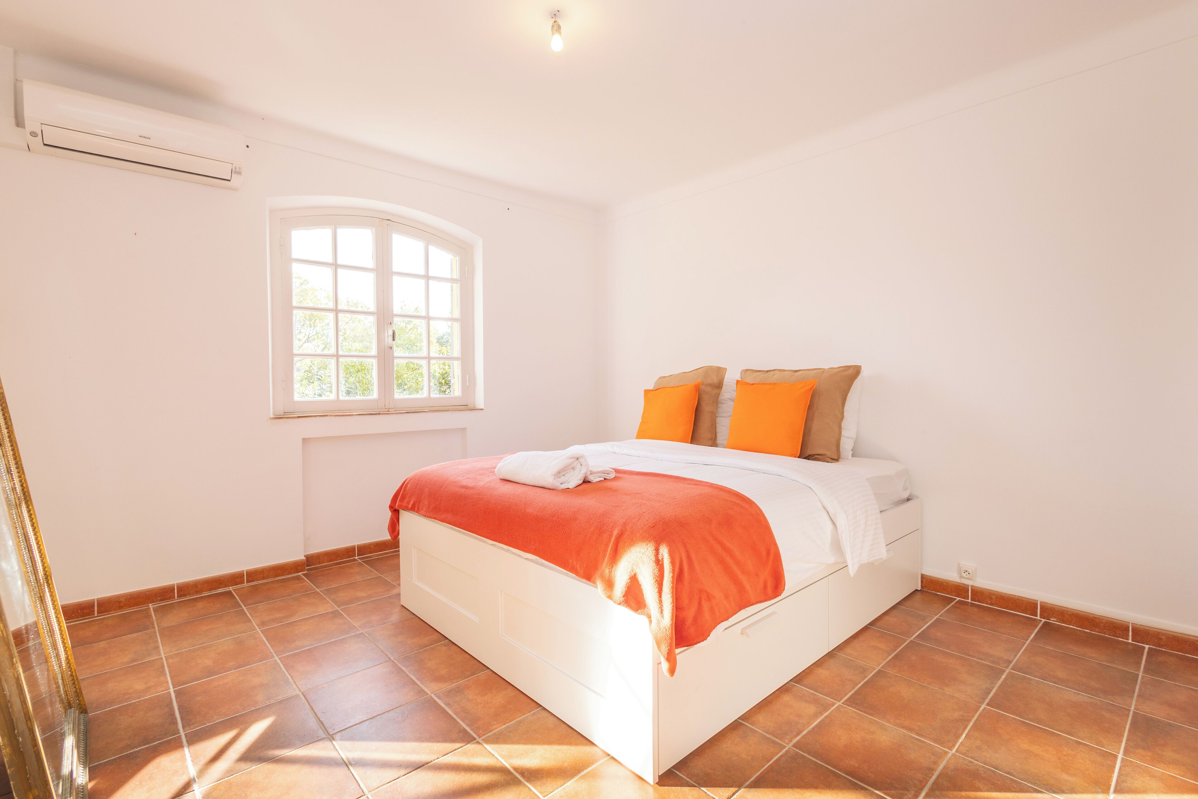 Une chambre à coucher avec un lit, une fenêtre et un sol carrelé.