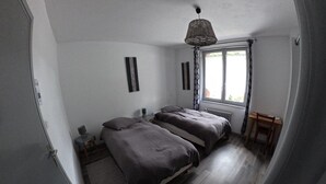 Un dormitorio con una cama grande, una mesita, una silla y una ventana con cortinas.