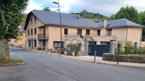 Un edificio de dos pisos con fachada de piedra, varios balcones y un acceso con reja.