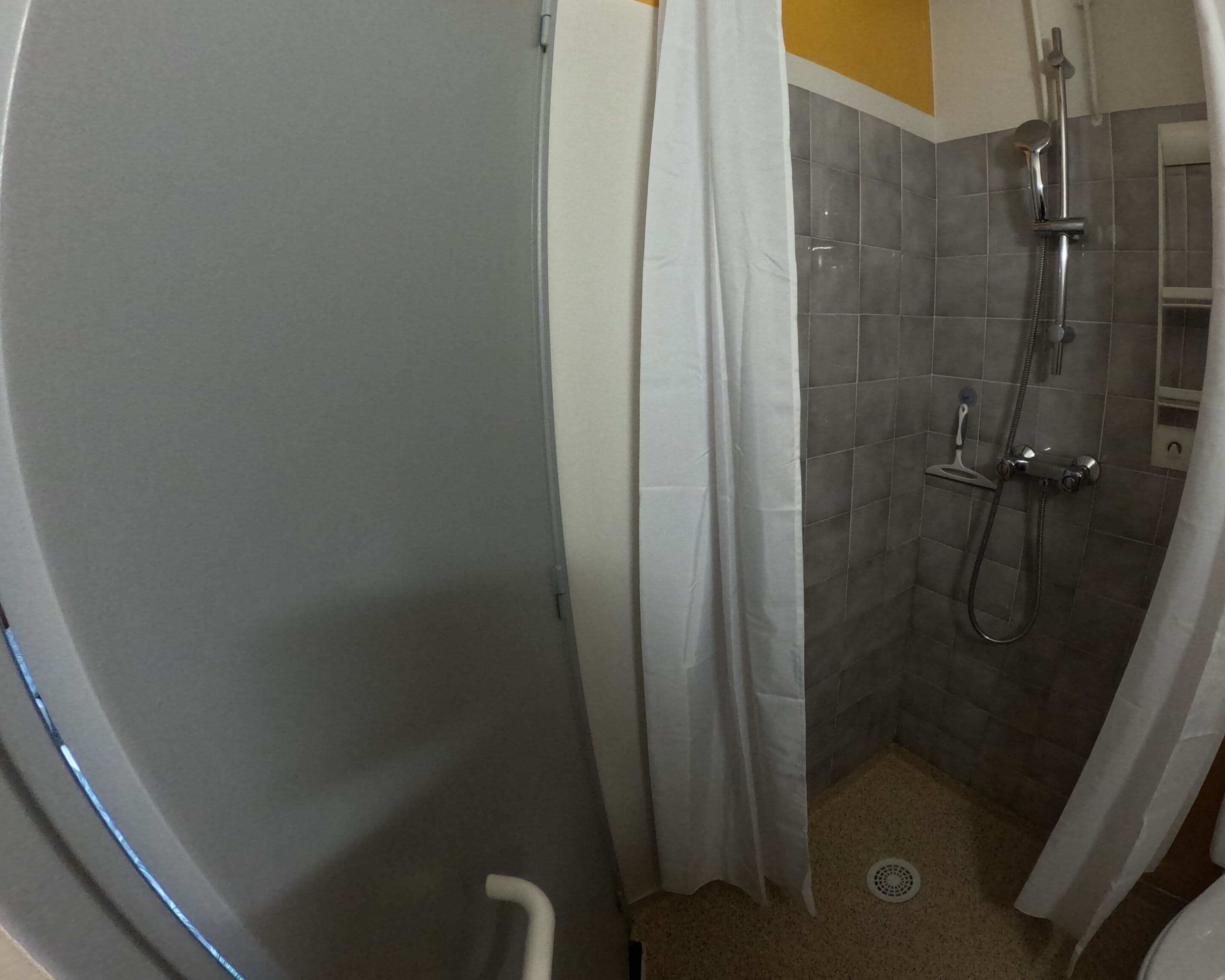 Un espace douche équipé d’un pommeau de douche, d’un pommeau de douche à main et d’un drain.