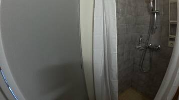 Un espace douche équipé d’un pommeau de douche, d’un pommeau de douche à main et d’un drain.