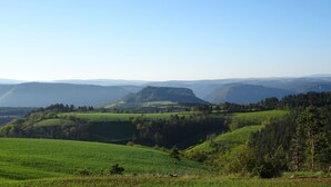 Una vista panorámica de ondulantes colinas verdes y montañas distantes bajo un cielo despejado.