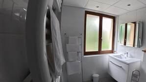 Un baño moderno con ducha, inodoro, lavamanos y espejo.