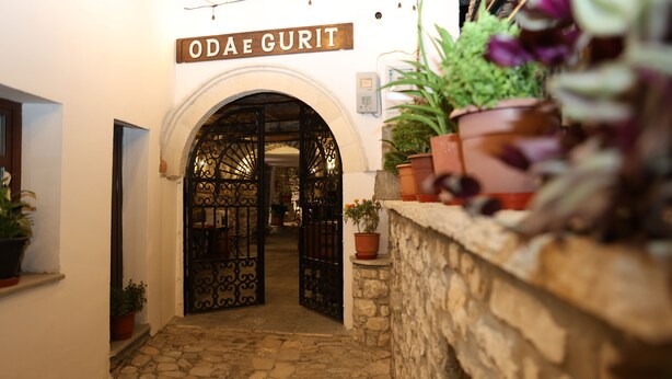 Una entrada con un letrero que dice "Odae Gurit" que da acceso a un patio empedrado.