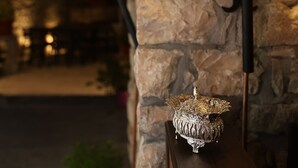 Una pared de piedra con dos luces adosadas y un cuenco decorativo de metal.
