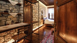 Una habitación rústica con pared de piedra, muebles de madera y una cama con ventana.