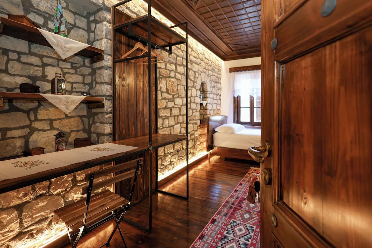 Una habitación rústica con pared de piedra, muebles de madera y una cama con ventana.