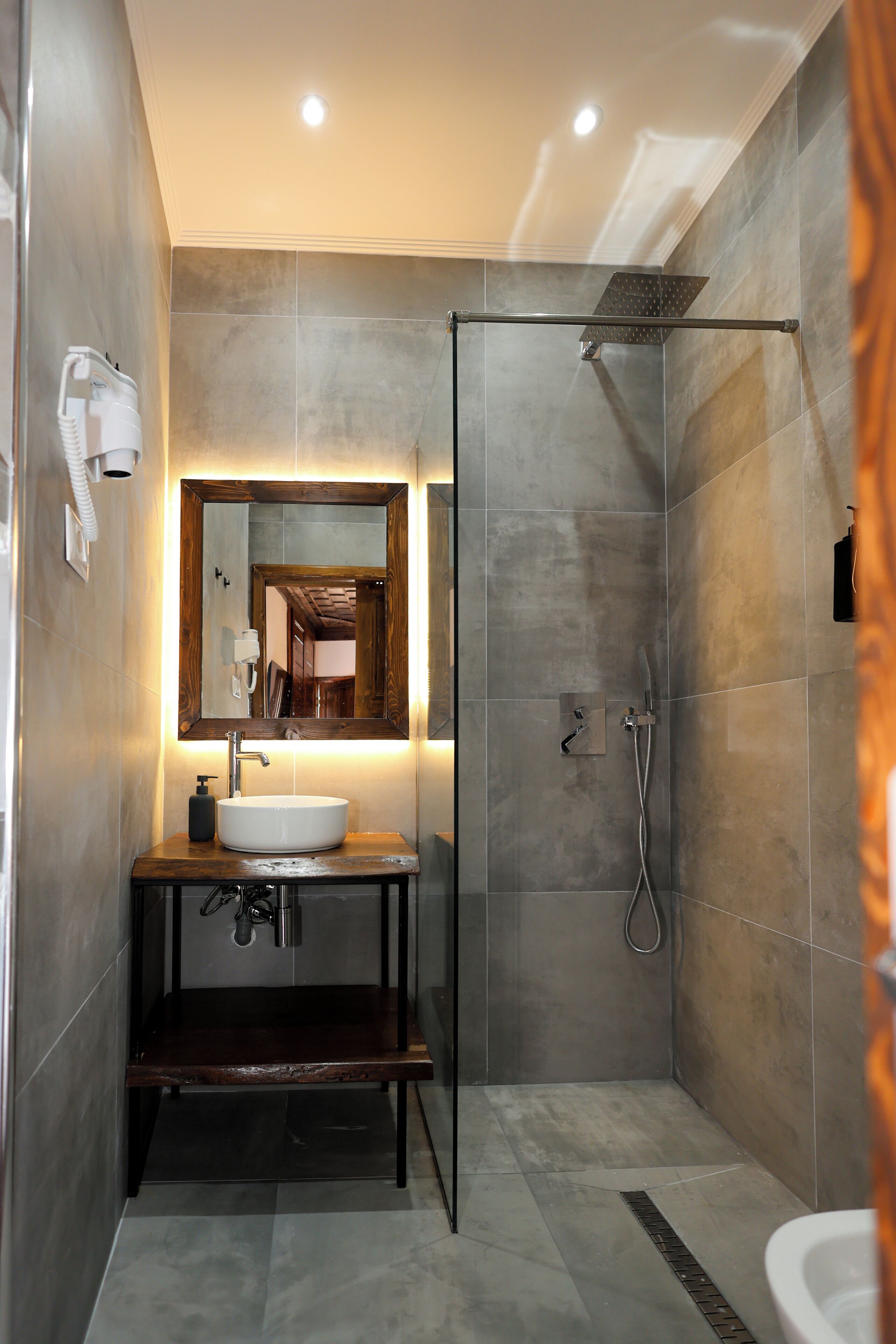 Une salle de bain moderne avec un grand miroir, un lavabo, une douche et des toilettes.