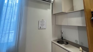 Eine kleine Küchenzeile mit integrierter Klimaanlage, einem Spülbecken und einem Schrank.