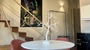 Ein modernes Zimmer mit einem weißen Tisch, rosafarbenen Stühlen, einer Treppe und einem großen abstrakten Gemälde.