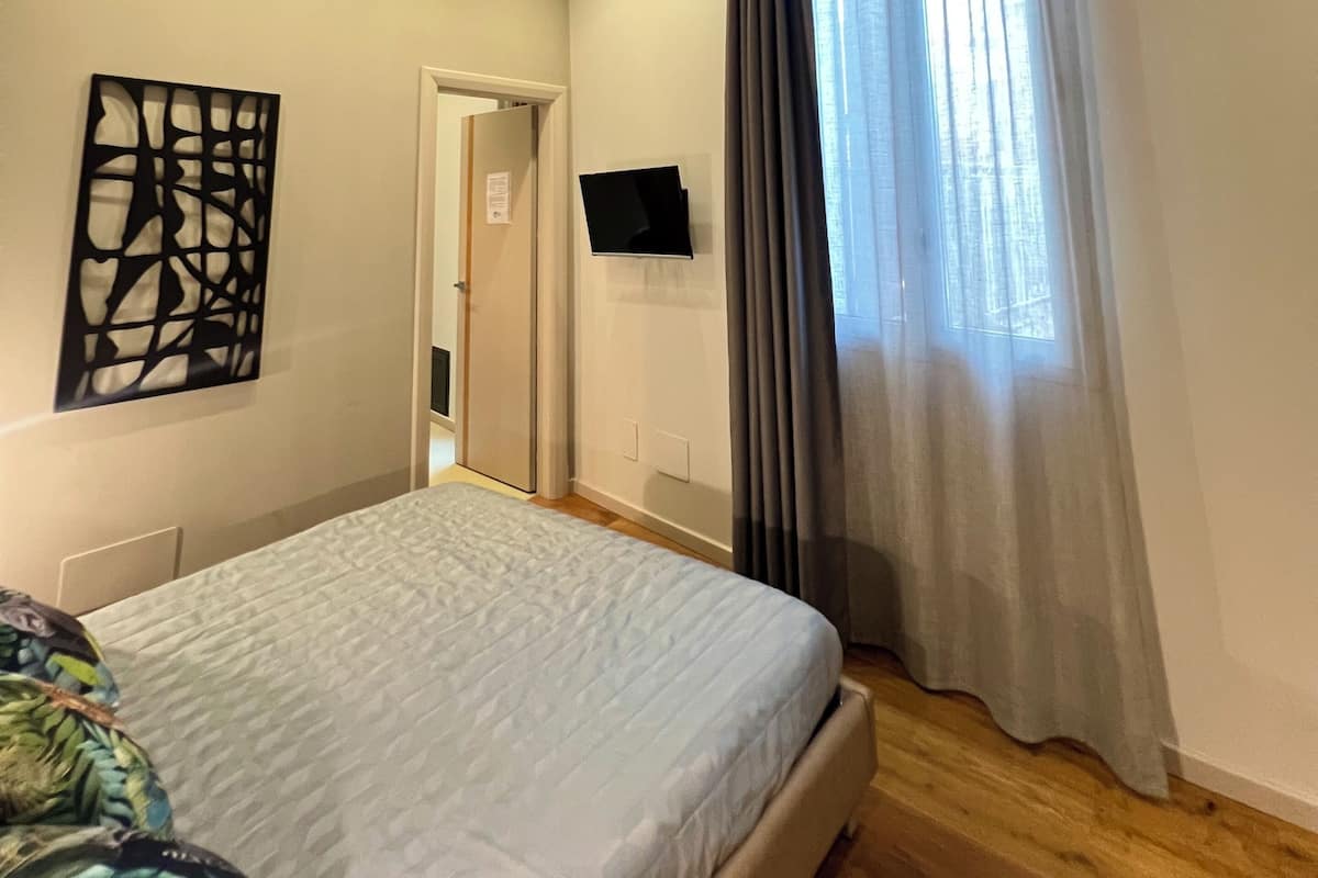 Een slaapkamer met een bed, een wandtelevisie, een deur en een airconditioning.