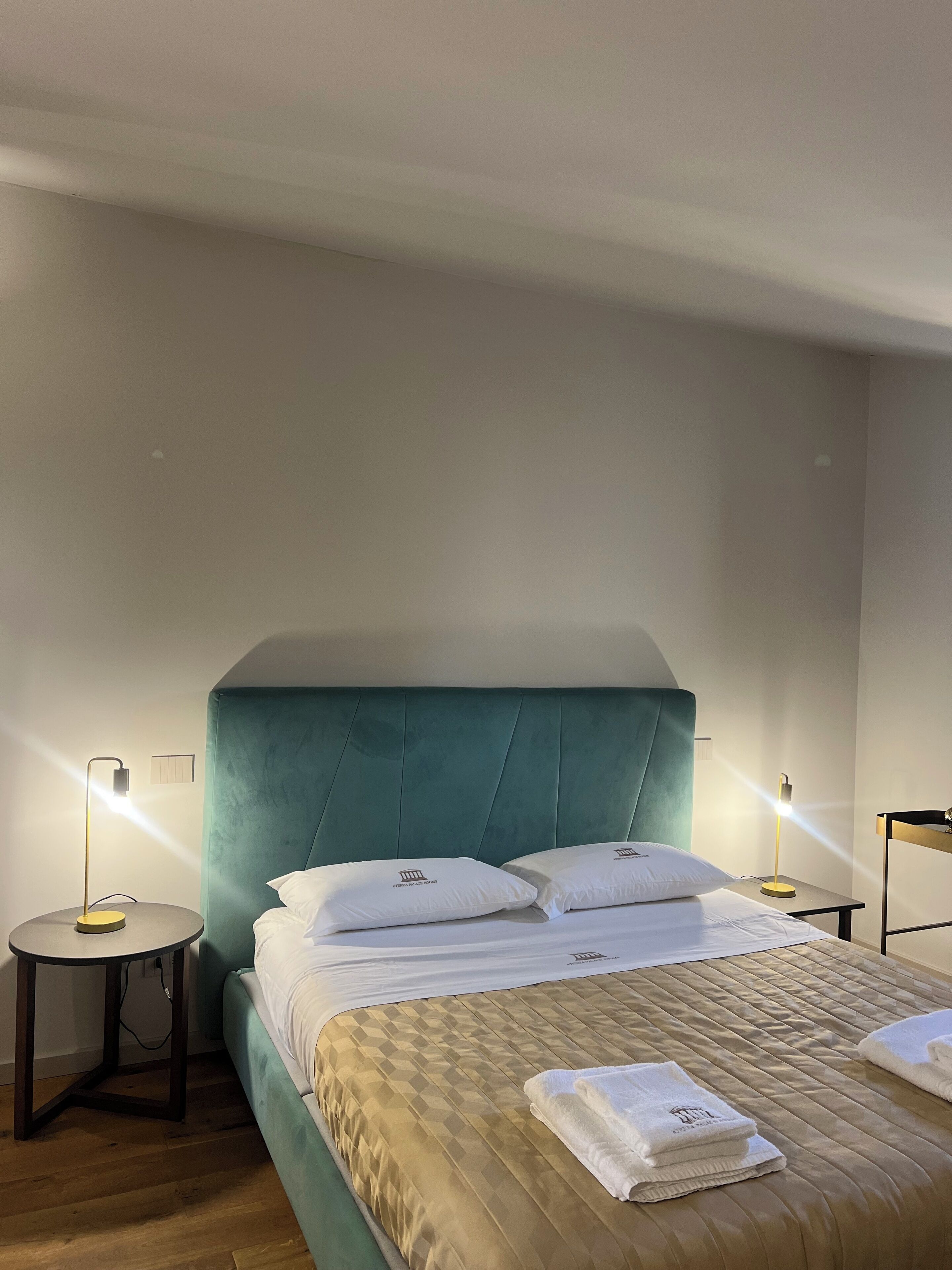 A hotel room with a bed, two bedside tables, and a headboard.