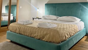 Ein Schlafzimmer mit einem großen Bett, einem Spiegel und einem Nachttisch mit Lampe.