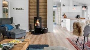 A modern living room with a wood-burning stove, grey sofas, and a kitchen in the background. - "Eilke" - 2km from the sea by Interhome (Ålbæk)