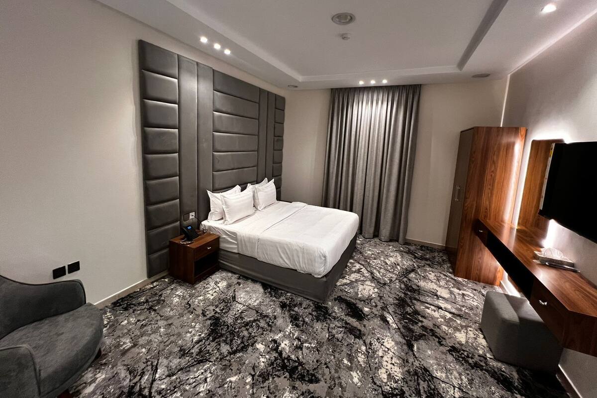 Una habitación de hotel moderna con una cama grande, un escritorio, una silla y un televisor.
