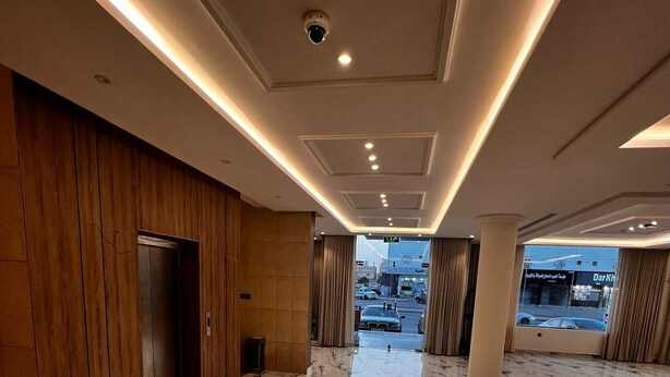Eine großzügige Lobby mit Marmorboden, Holzvertäfelung an einer Wand und Blick auf die Straße durch ein großes Fenster.