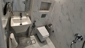 Ein modernes Badezimmer mit Marmorwand, integriertem Waschbecken, Toilette und Dusche.