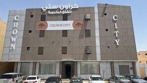 Ein Gebäude mit der Aufschrift „CROWN CITY“, das ein modernes Design mit einer Kombination aus grau- und beigetonierten Fassadenelementen aufweist.