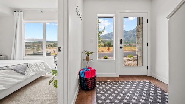 Un dormitorio con cama, ventana, puerta que da al exterior y una pequeña mesa con una planta.