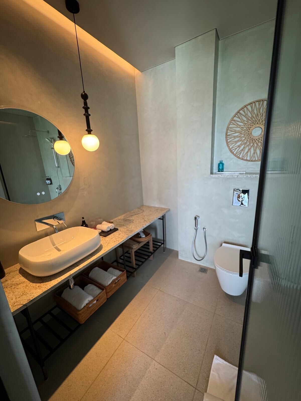 Ein modernes Badezimmer mit einem großen, ovalen Waschbecken, einem Spiegel, einem Handtuchhalter, einer Dusche und einem dekorativen Wandbild.