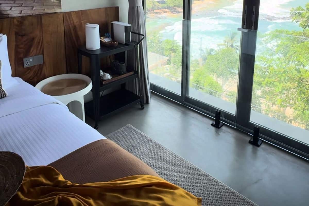 Une chambre d’hôtel dotée d’une grande fenêtre donnant sur un paysage côtier.