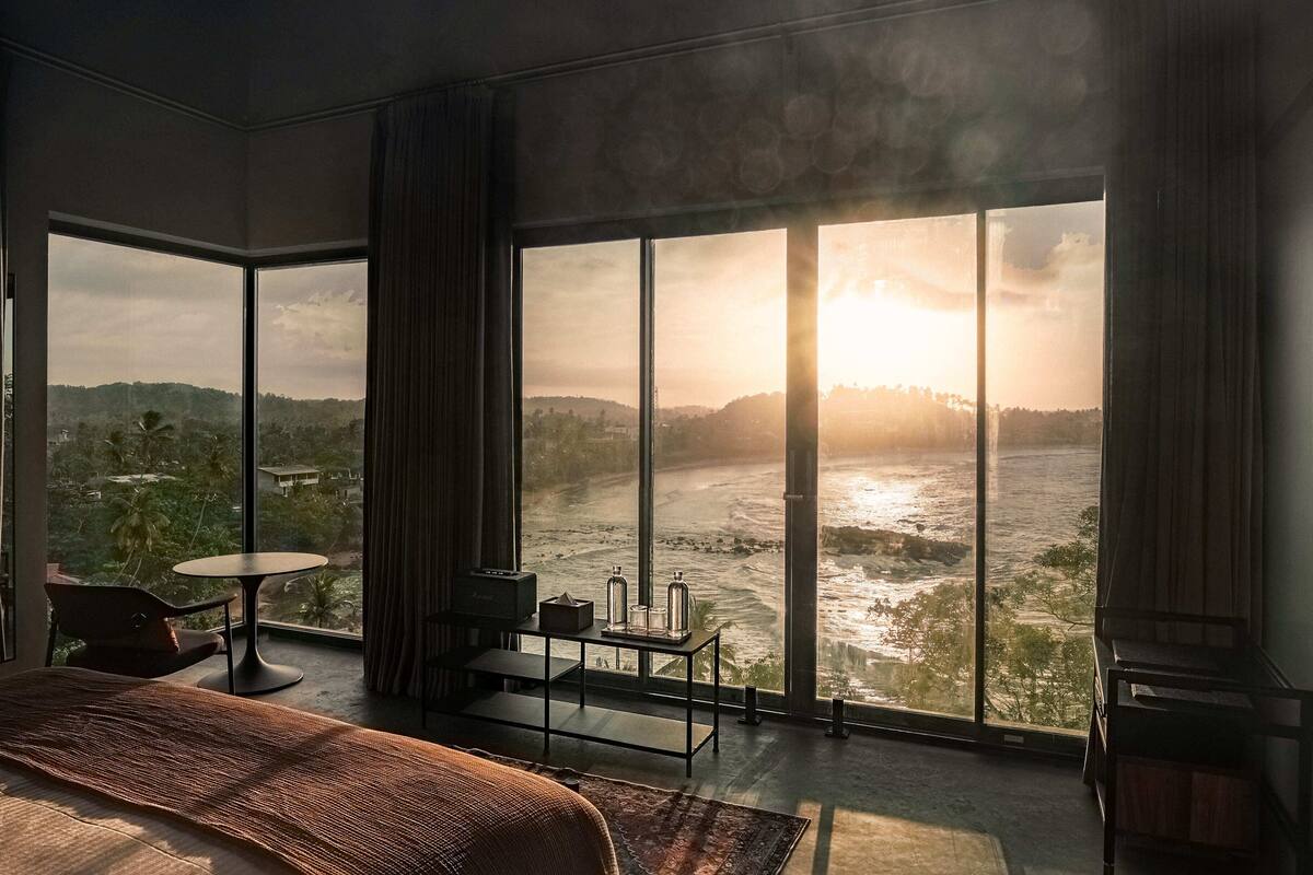 Une chambre spacieuse avec une grande fenêtre donnant sur une rivière et des collines.