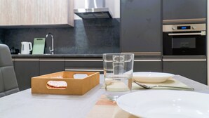 A modern kitchen with a wooden box, a glass of water, and a white plate on a table. - Apartamentos Doña Berenguela by gaiarooms (León)