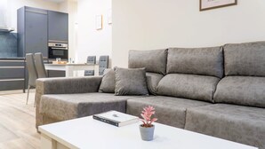 A modern living room with a grey sectional sofa, a white coffee table, and a potted plant. - Apartamentos Doña Berenguela by gaiarooms (León)