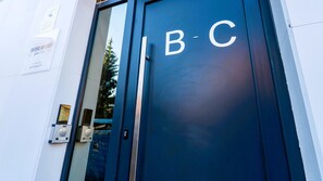 Una puerta azul con las letras "B-C", una puerta de cristal y una pequeña señal en la pared.