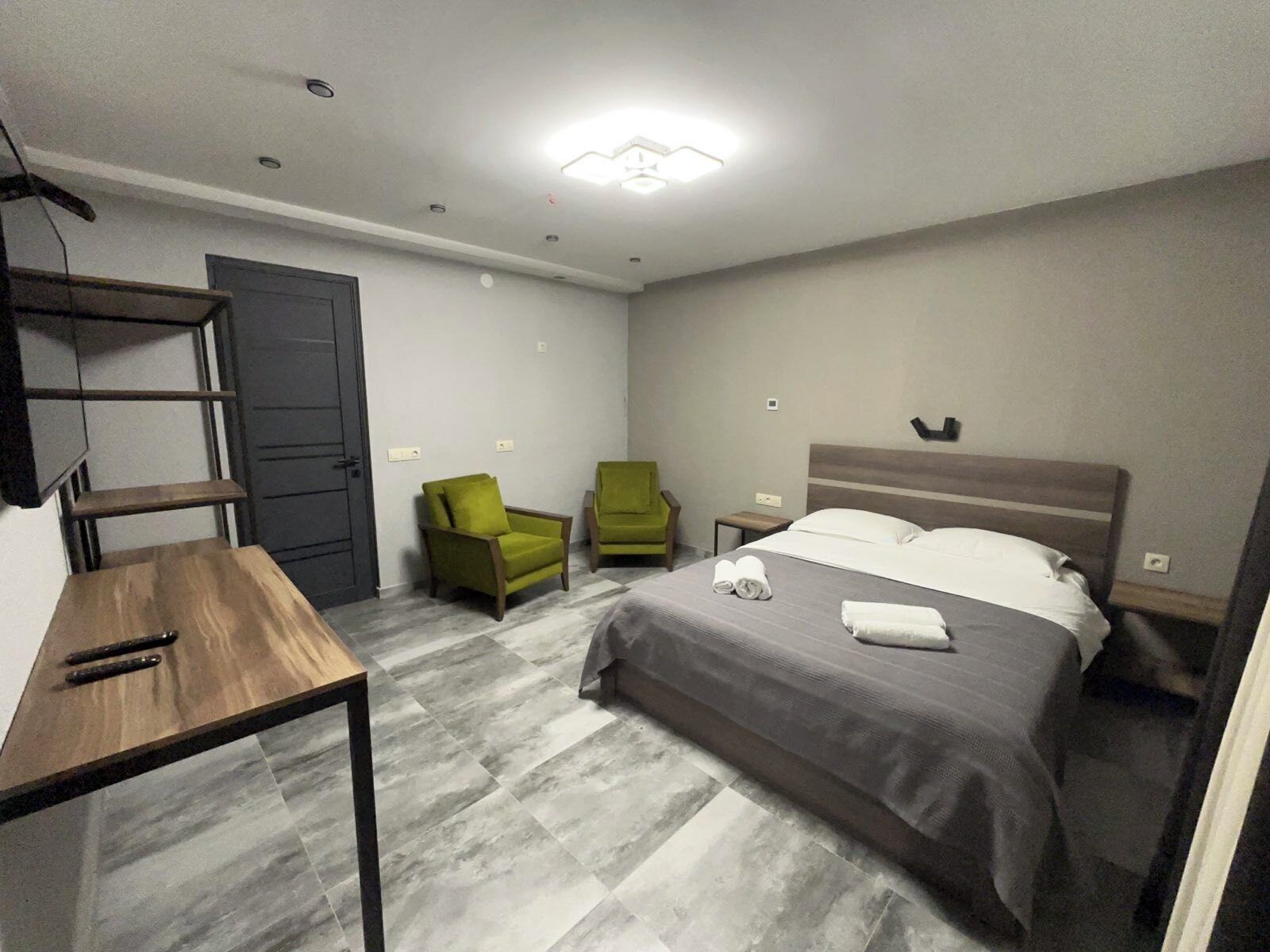 A hotel room with a bed, two chairs, a table, and a TV.