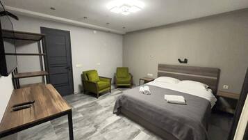 A hotel room with a bed, two chairs, a table, and a TV.