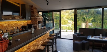 A modern kitchen with a stone backsplash, a built-in oven, and a large window overlooking a lush garden.