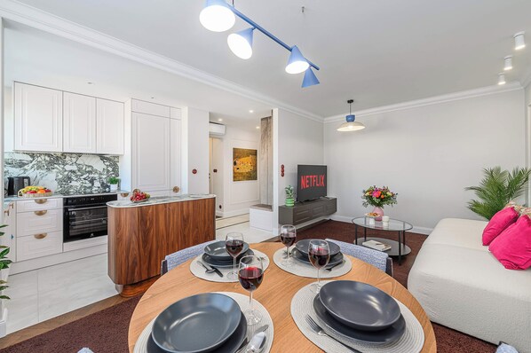 A modern living room with a dining area, white cabinetry, a TV, and a cozy seating area.