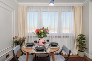 A dining area with a round table set for four, a vase of flowers, and a potted plant.