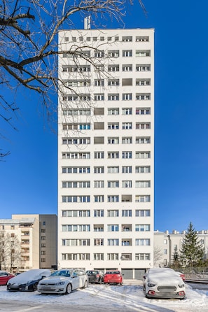 A tall, modern apartment building with multiple floors and numerous windows.