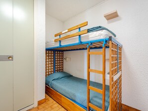 Uma cama beliche com escada de madeira e colchão azul.