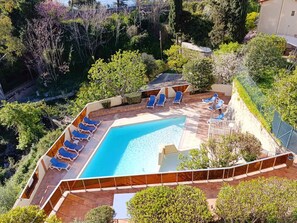 A swimming pool with blue lounge chairs, surrounded by greenery and a fenced area. - 6-person Apartment with Wi-Fi in Roquebrune-Cap-Martin (Roquebrune-Cap-Martin)