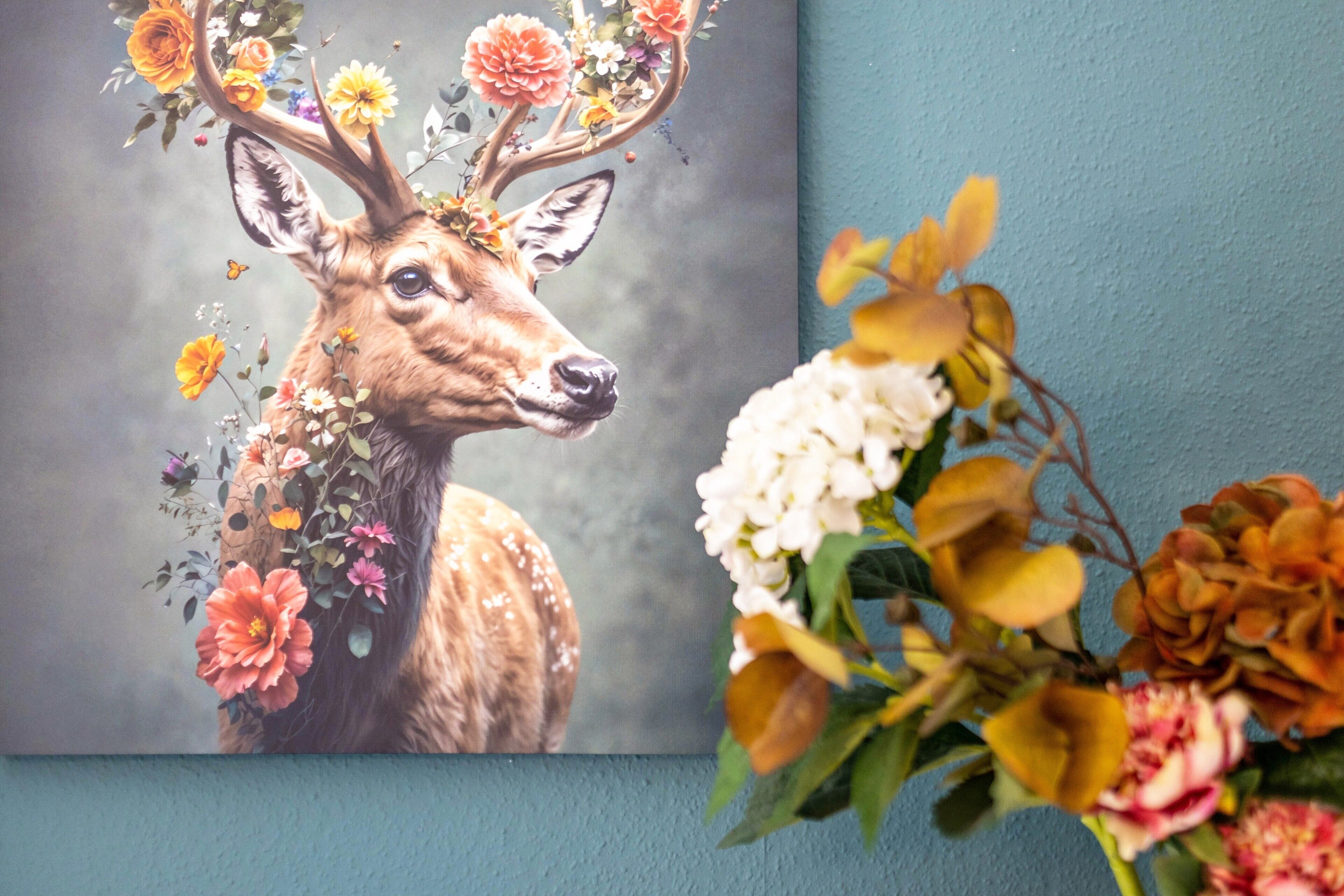 En hjort dekorerad med blommor, en blå vägg och en blomsteruppsättning.