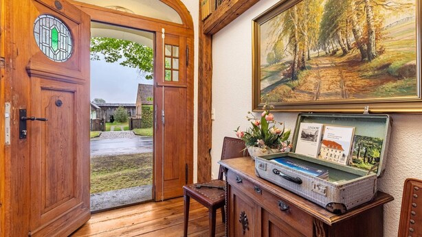 A wooden door with a glass window, a painting of a forest, and a vintage suitcase with travel brochures. - Apartment 2 with Shared Terrace and Wi-Fi (Lindow (Mark))