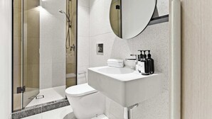 A modern bathroom with a glass-enclosed shower, a white sink with toiletries, and a large mirror. - Luxury Stay Near Grand Prix Track (Melbourne)