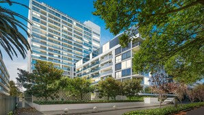 A modern multi-story building with balconies, surrounded by greenery and a clear sky. - Luxury Stay Near Grand Prix Track (Melbourne)