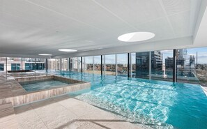 Ein moderner, überdachter Swimmingpool mit Blick auf die Stadtlandschaft.