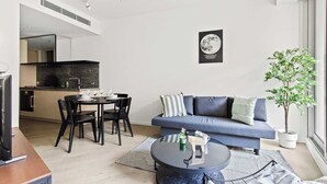 A modern living room with a sofa, coffee table, and dining area. - Luxury Stay Near Grand Prix Track (Melbourne)