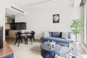 A modern living room with a sofa, coffee table, and dining area. - Luxury Stay Near Grand Prix Track (Melbourne)