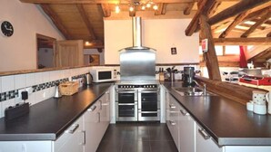 A modern kitchen with a central island, stainless steel appliances, and a wooden ceiling. - Chalet Bronziers - authentic alpine experience (10p, sauna) (Peisey-Nancroix)