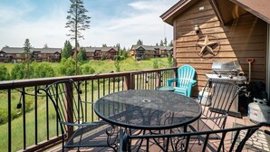 A balcony with a metal table and chairs, a grill, and a view of other buildings. - 177 Wildflower - Mountain Home with New Hot Tub (Fraser)