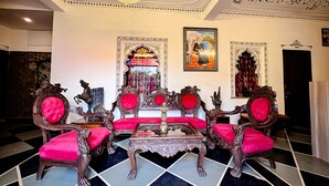 A luxurious room with ornate furniture, a chandelier, and a large mirror. - Hotel Kanak Niwas (Udaipur)
