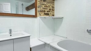 Een badkamer met een witte wastafel, een bad en een spiegel.