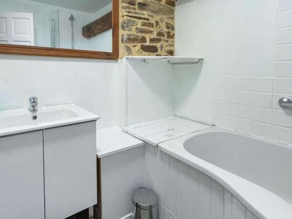 A bathroom with a white sink, a bathtub, and a mirror.