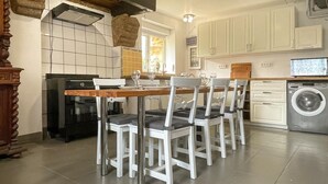 Een keuken met een eettafel, stoelen, een wasmachine en een fornuis.